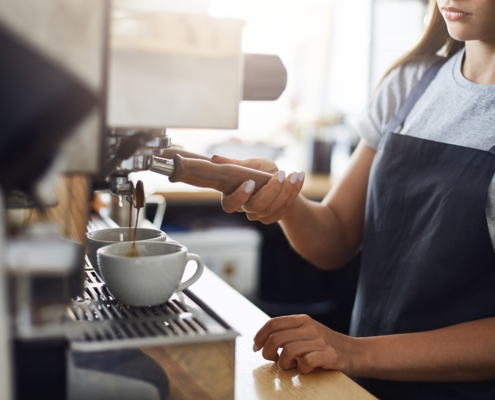 Barista preparing a cup of coffee using a commercial coffee machine.